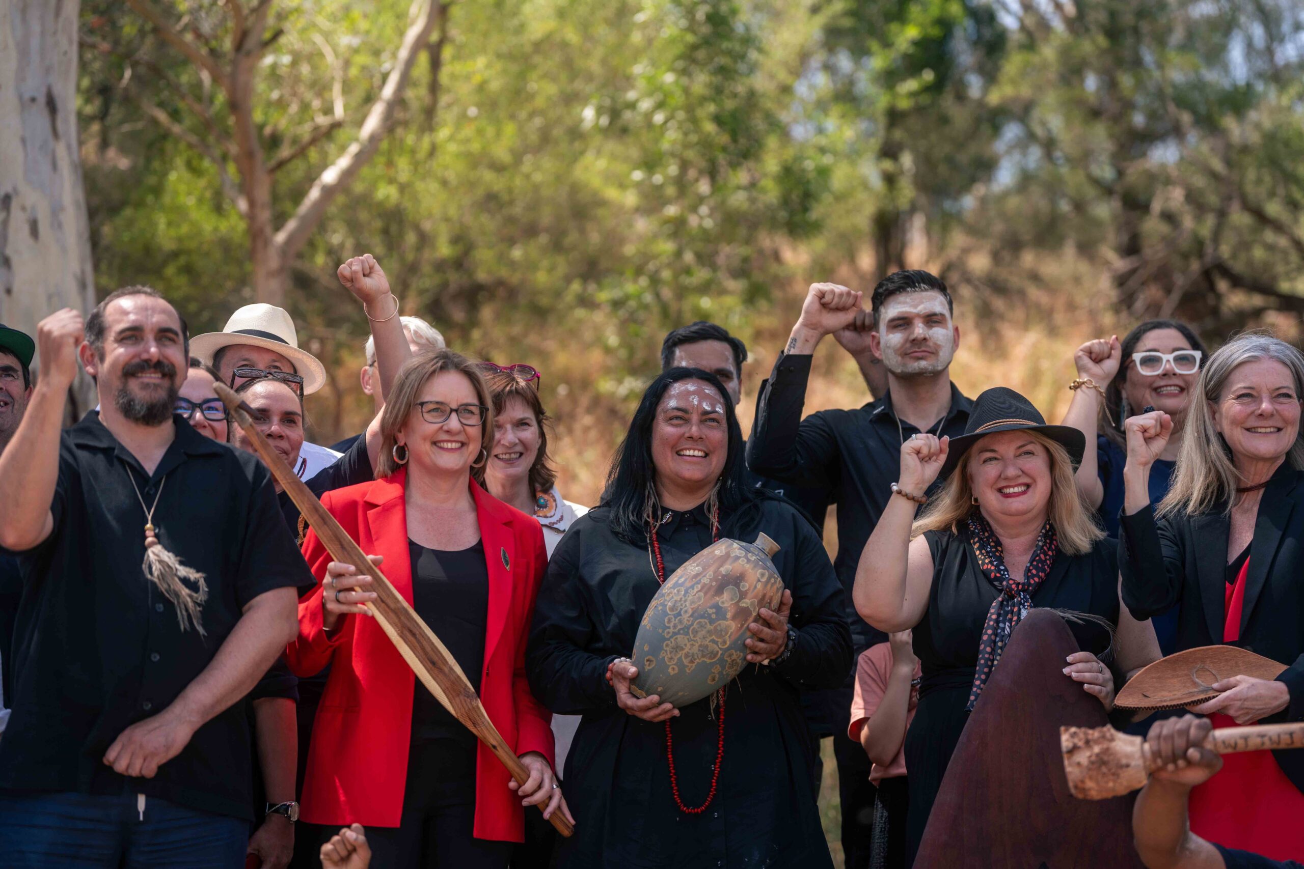 First Peoples' Assembly of Victoria and Victorian Government members welcome the opening of Statewide Treaty negotiations as a group, smiling with fists raised in the air.