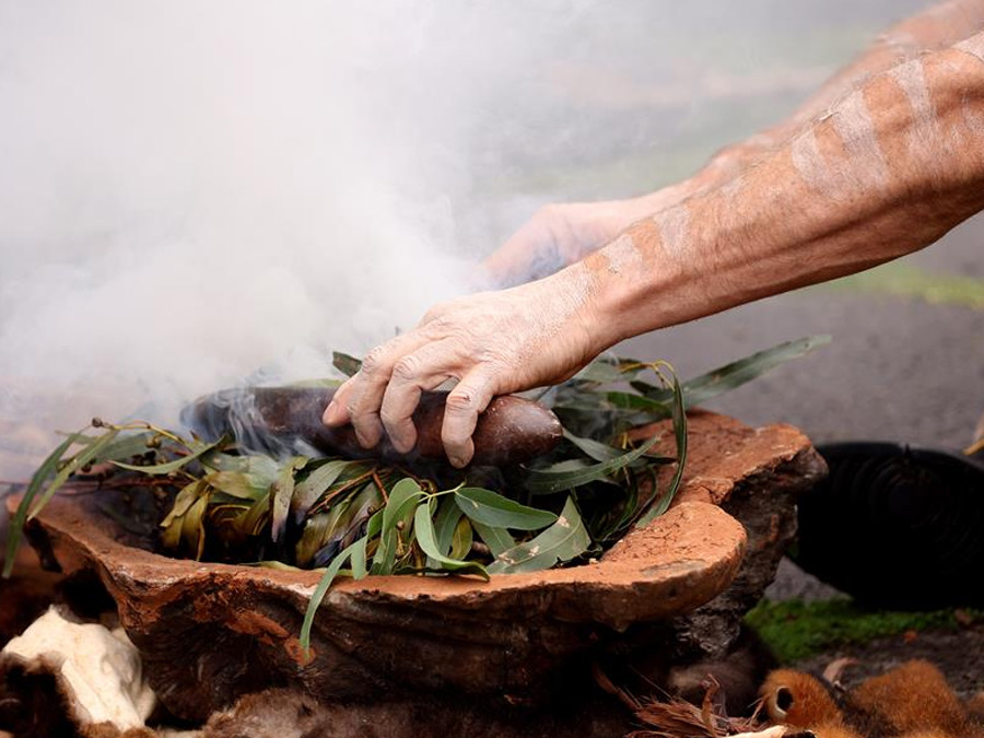 Close up hands performing a smoking ceremony at a Welcome to Country.